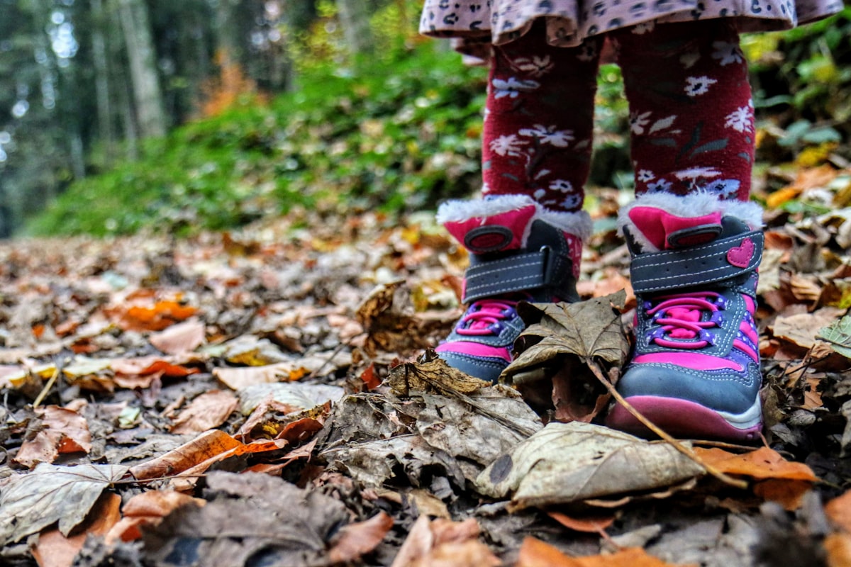 Toddler wearing hiking boots stepping on rocks on a forest trail