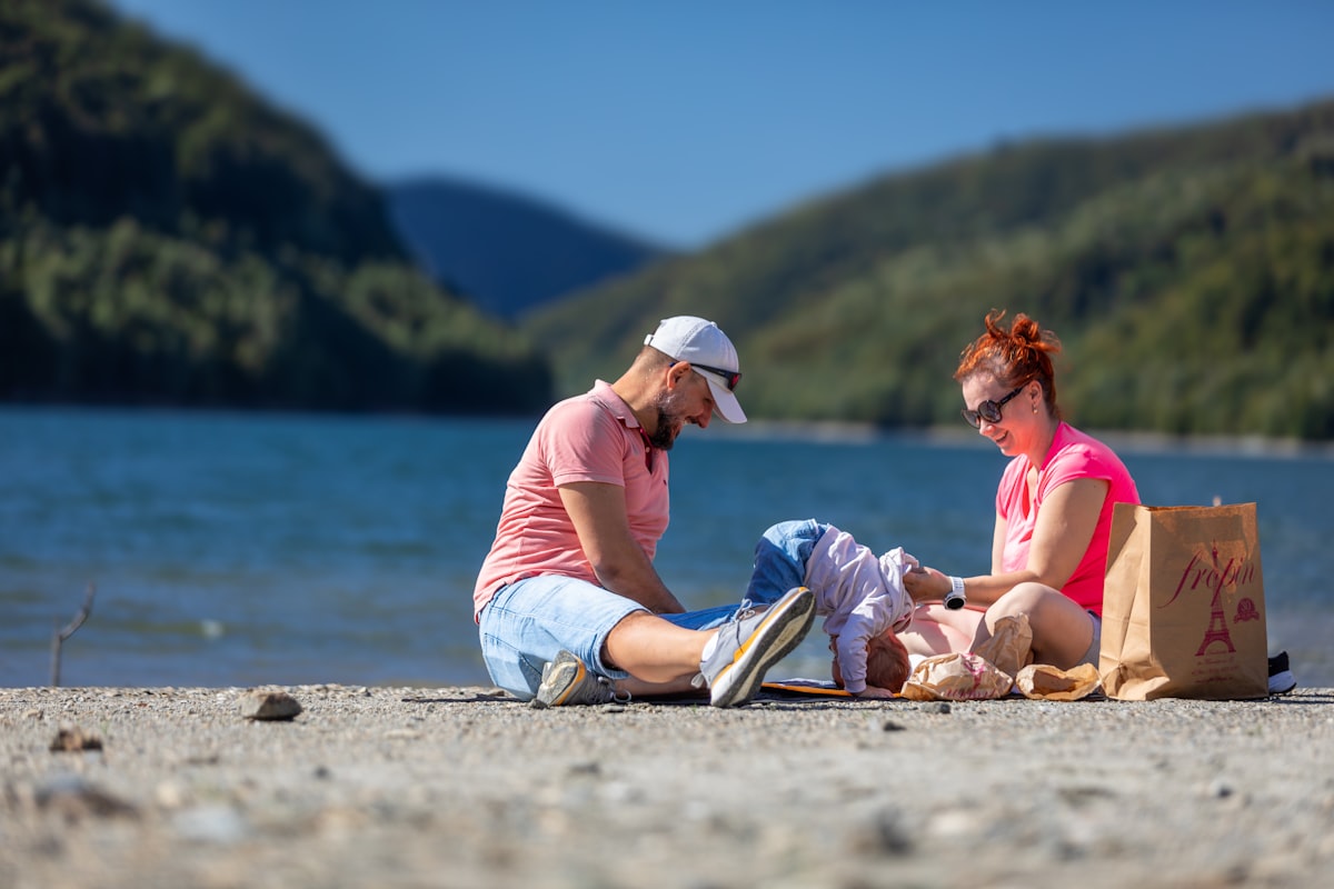 Parent kneeling to help young child try on hiking boots at a trailhead