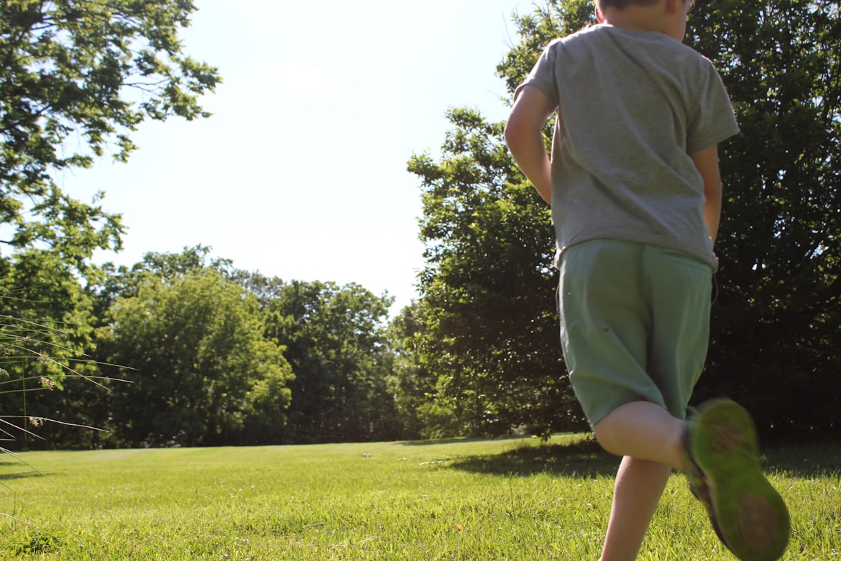 Young children running and playing freely in a grassy park on a sunny day