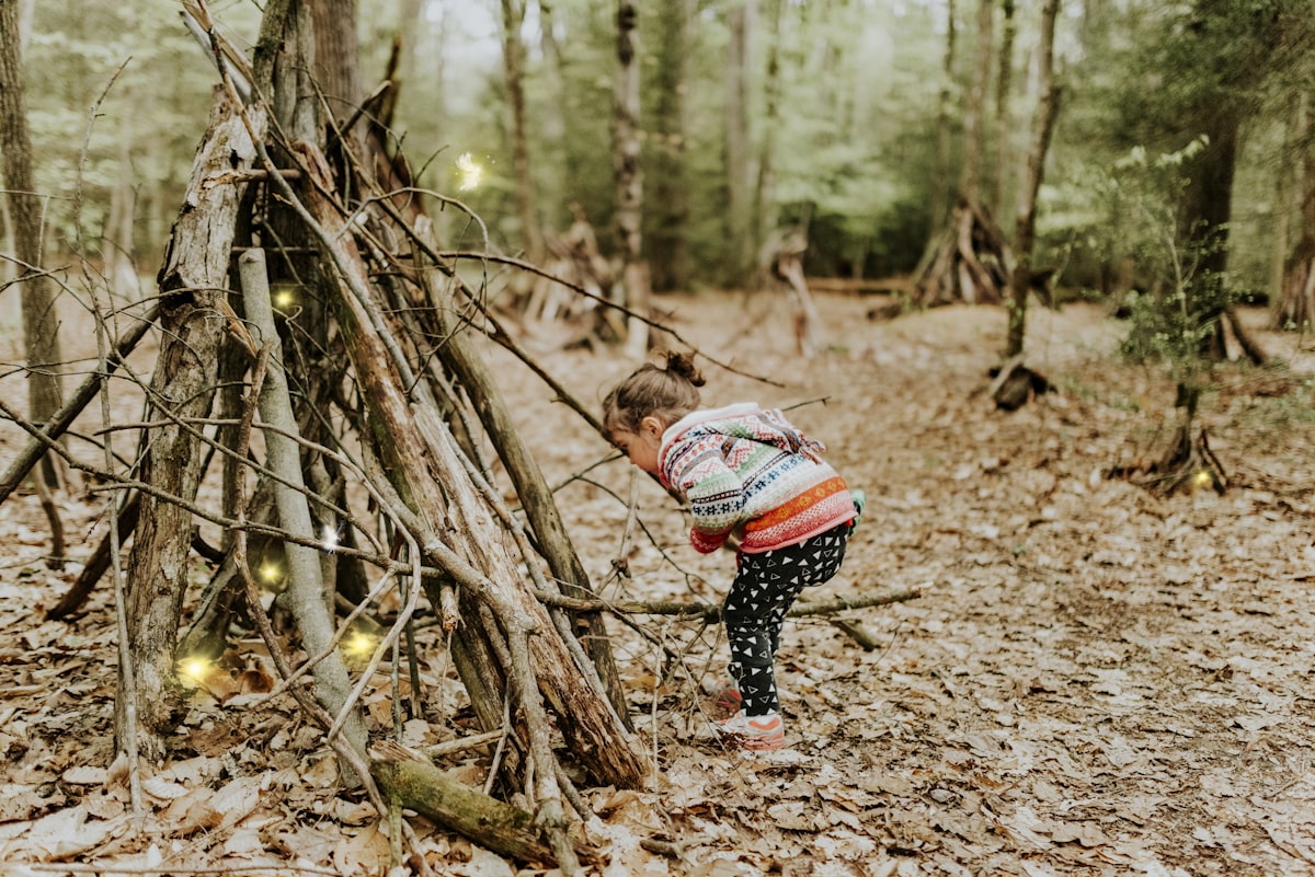 Young toddler crouching down to explore nature on a sunny day at the park