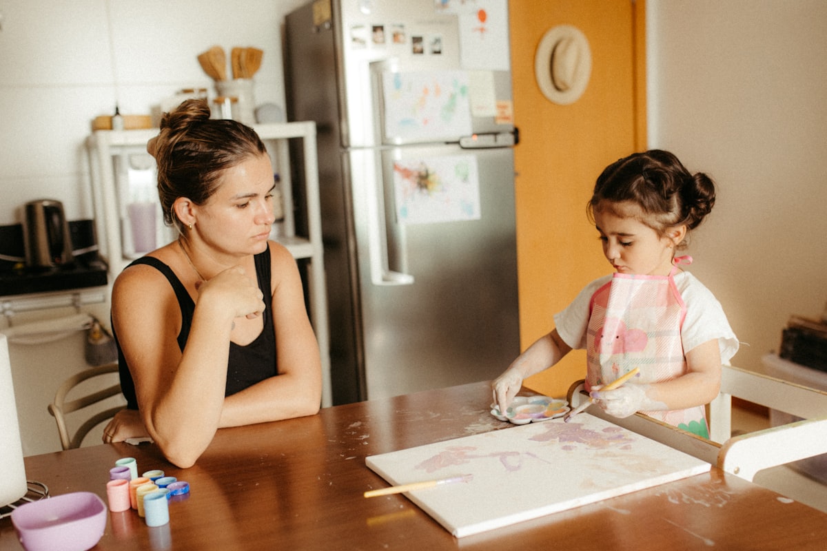 Young child sitting at a table engaged in hands-on playdough sensory play indoors