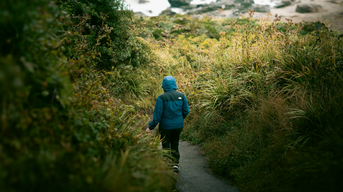 Two young children wearing hiking boots on a rocky trail surrounded by trees